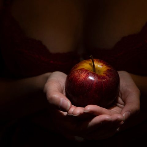 Seductive woman in lingerie with apple in hand